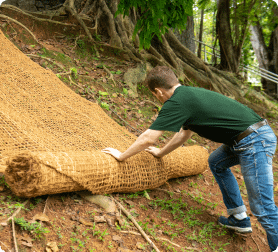 Experts at HEIGER Australia unrolling coir geotextiles on eroded slopes to prevent sediment run off
